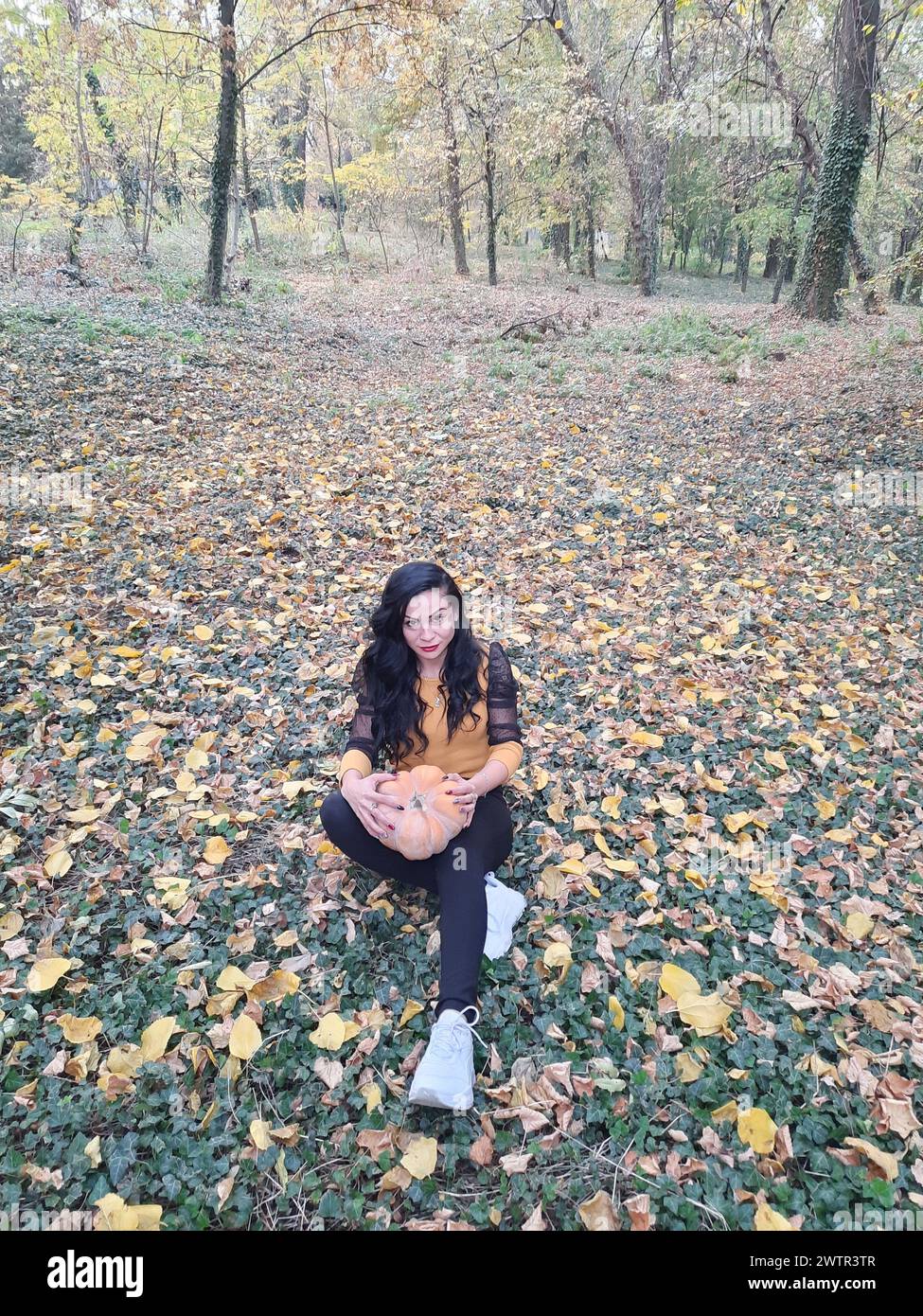Ein Mädchen liegt auf dem Rücken in der Natur mit Herbstlaub Stockfoto