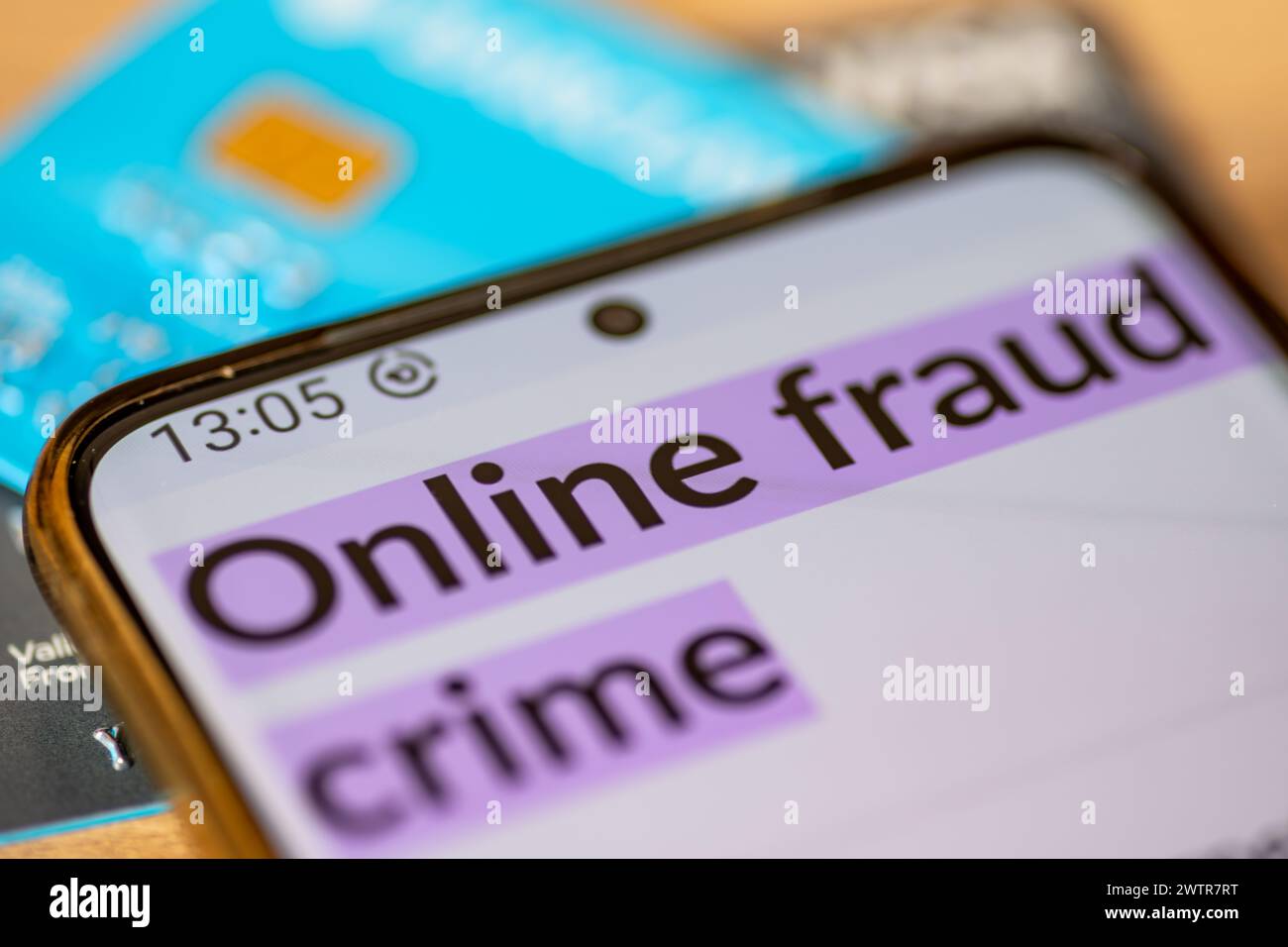 Eine Makroaufnahme eines Mobiltelefons mit den Worten Online-Betrug Verbrechen auf Kredit, Debit-Bankkarten. Ein Konzept der Online-Betrugskriminalität. Stockfoto