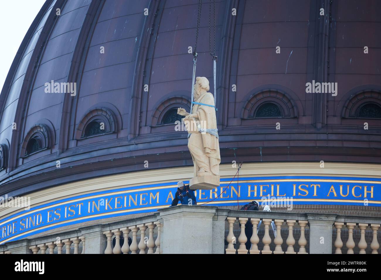 Berlin, Deutschland. März 2024. Eine Skulptur des Propheten Jeremia, die für die Kuppelbalustrade des Humboldt-Forums bestimmt ist, schwebt über ihrem Ziel, wie sie installiert ist. Insgesamt acht Figuren sind Teil des umfangreichen historischen Ensembles freistehender Figuren, die alle heute und morgen installiert werden sollen. Es sind die acht biblischen Propheten Jesaja, Hosea, Zephanja, Sacharja, Jonah, Daniel, Jeremiah und Ezekiel. Quelle: Jörg Carstensen/dpa/Alamy Live News Stockfoto