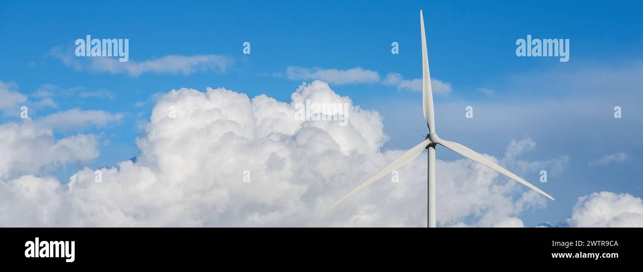 Panoramablick auf die Schaufeln einer Windturbine über einem blauen Himmel mit großen Wolken. Stockfoto