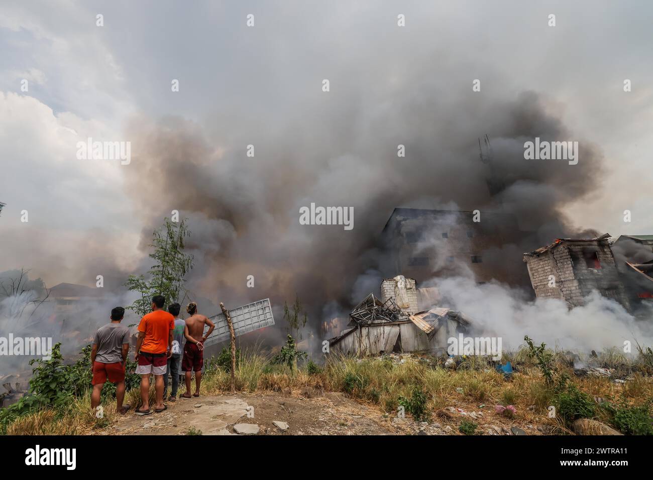 Quezon City, Philippinen. März 2024. Die Einwohner stehen in der Nähe verbrannter Gebäude in Quezon City, den Philippinen, 19. März 2024. Nach Angaben der örtlichen Behörden waren etwa 400 Familien von einem Feuerunfall betroffen, der sich am Dienstag in Quezon City ereignete. Quelle: Rouelle Umali/Xinhua/Alamy Live News Stockfoto