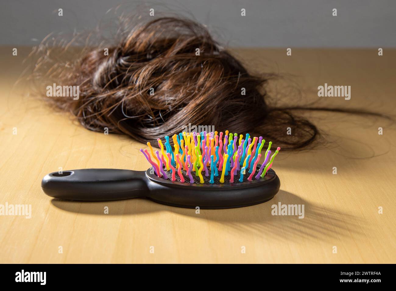 Bunte Haarbürste neben den Haarsträhnen der Frau Stockfoto
