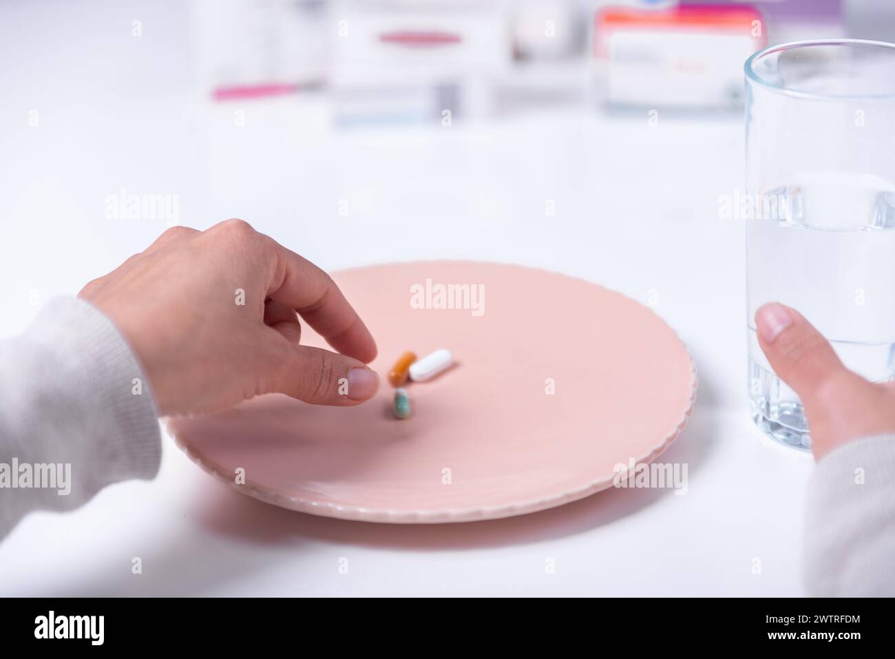 Eine rekonvaleszierende Person, die gerade eine von drei Pillen nehmen wird, die zu diesem Zeitpunkt fällig sind. Stockfoto