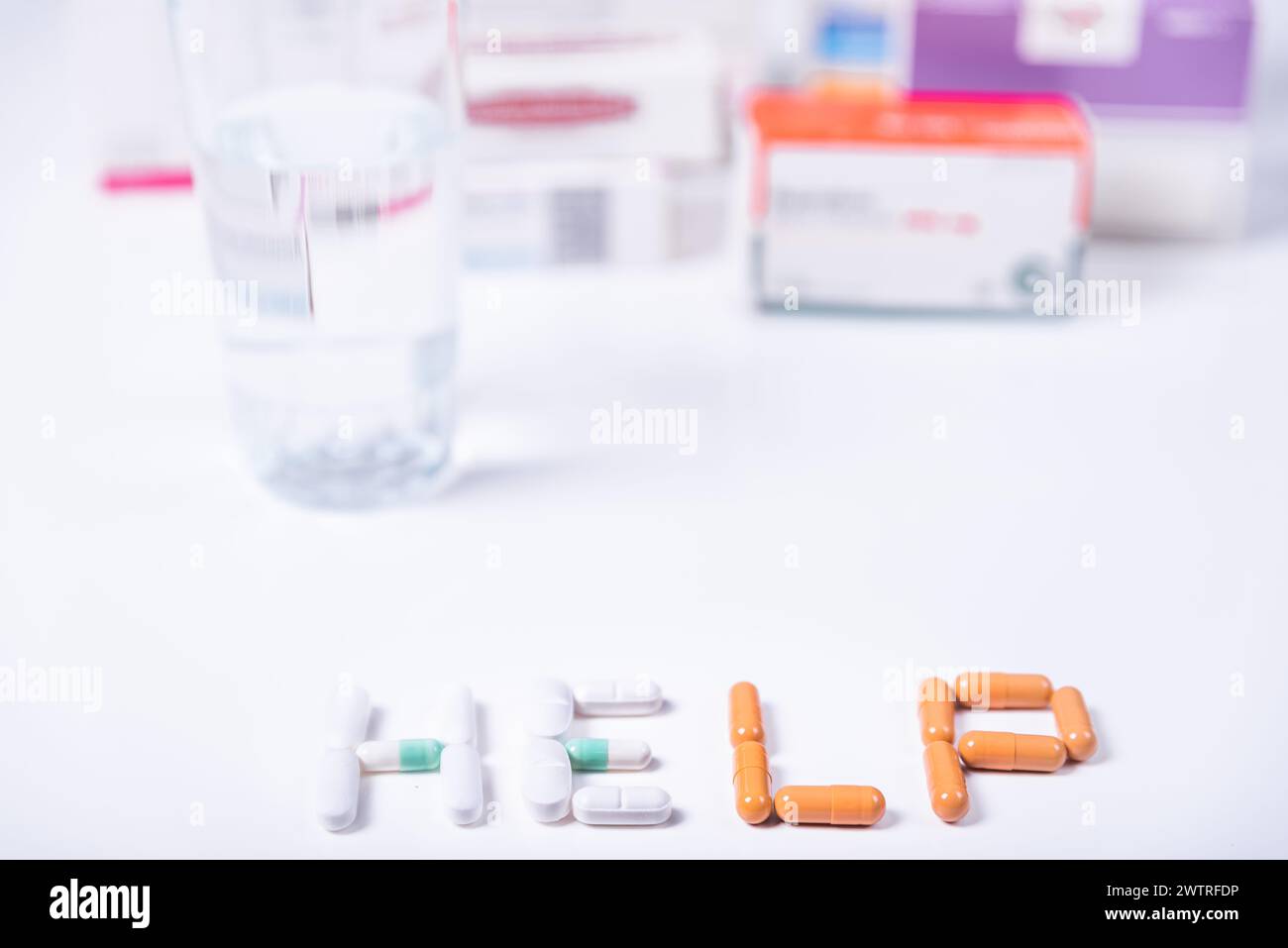 Wort HILFE gemacht mit medizinischen Pillen und im Hintergrund mehrere Kisten von Medikamenten. Stockfoto