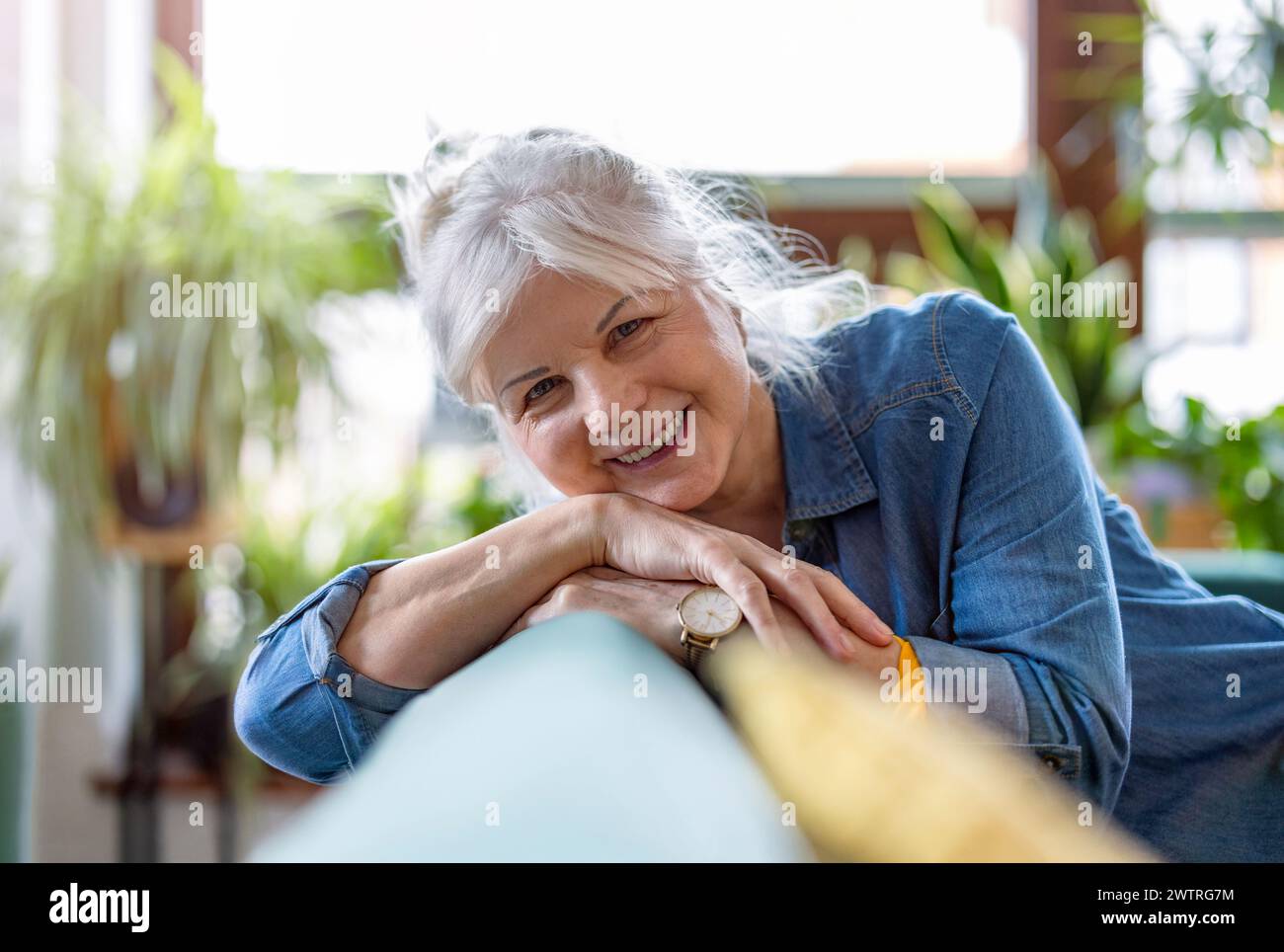 Porträt der lächelnde senior Frau sitzt auf dem Sofa im Wohnzimmer zu Hause Stockfoto