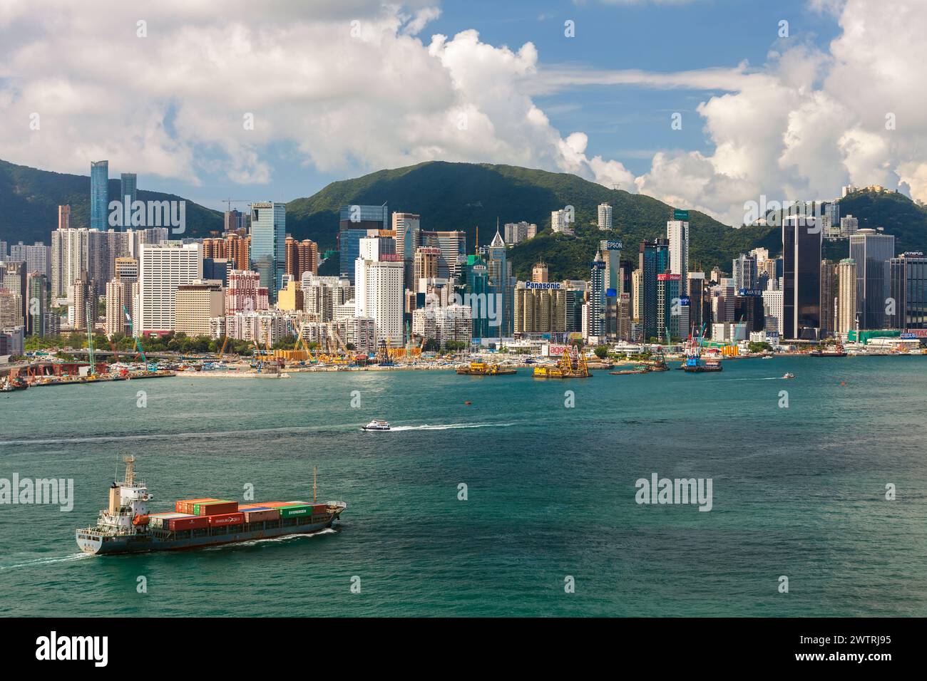HONGKONG - 3. Juni 2015: Luftaufnahme eines Containerschiffs vor der Skyline des Victoria Harbour von Hongkong, 3. Juni 2015, Hongkong, China. Stockfoto