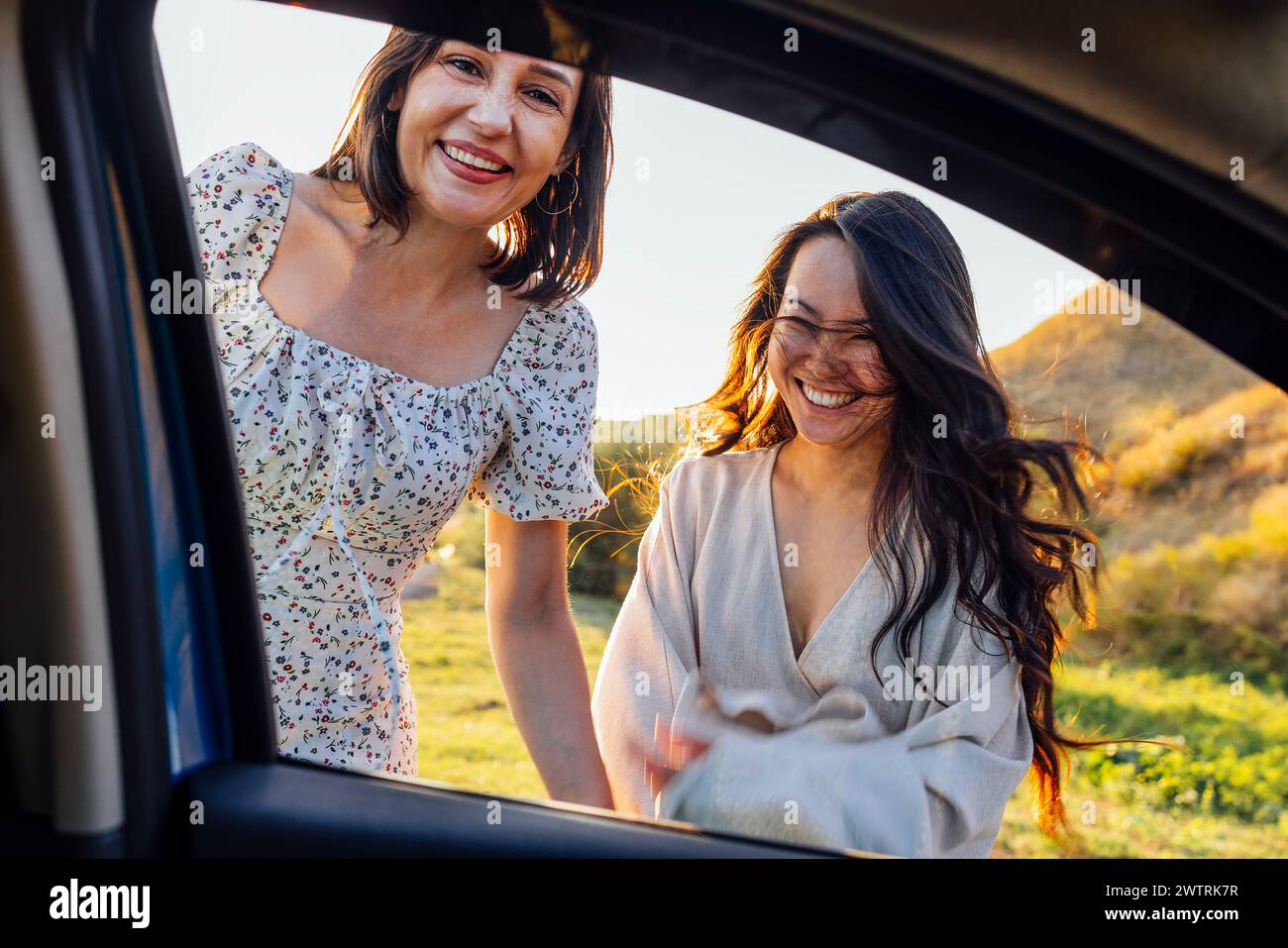 Junge Frauen verschiedener Rassen lachen und haben Spaß während der Reise. Charmante multiethnische Freunde im Sommer kleiden sich in der Natur entspannen Stockfoto