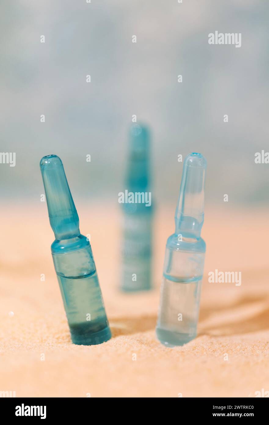 Nahaufnahme von blauen Ampullen mit intensivem Feuchtigkeitskonzentrat mit Hyaluronsäure und Vitaminen auf Sandgrund. Set von Gesichtsseren mit p Stockfoto