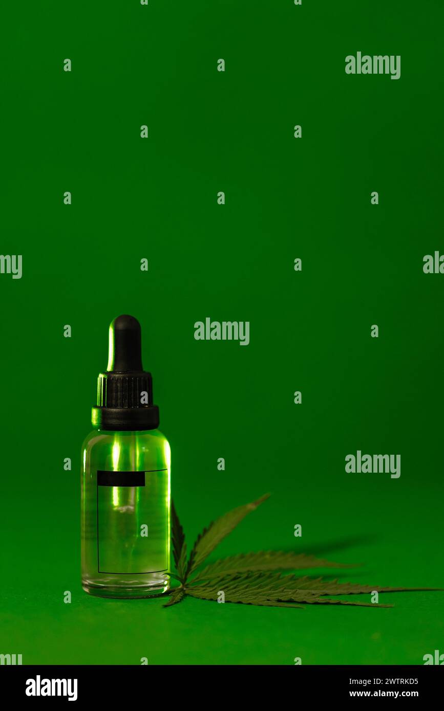 Eine nachgeahmte transparente Glasflasche mit einer Pipette mit einem feuchtigkeitsspendenden Konzentrat mit Hyaluronsäure und einem Blatt Cannabis. Gesichtsserum mit Peptid Stockfoto