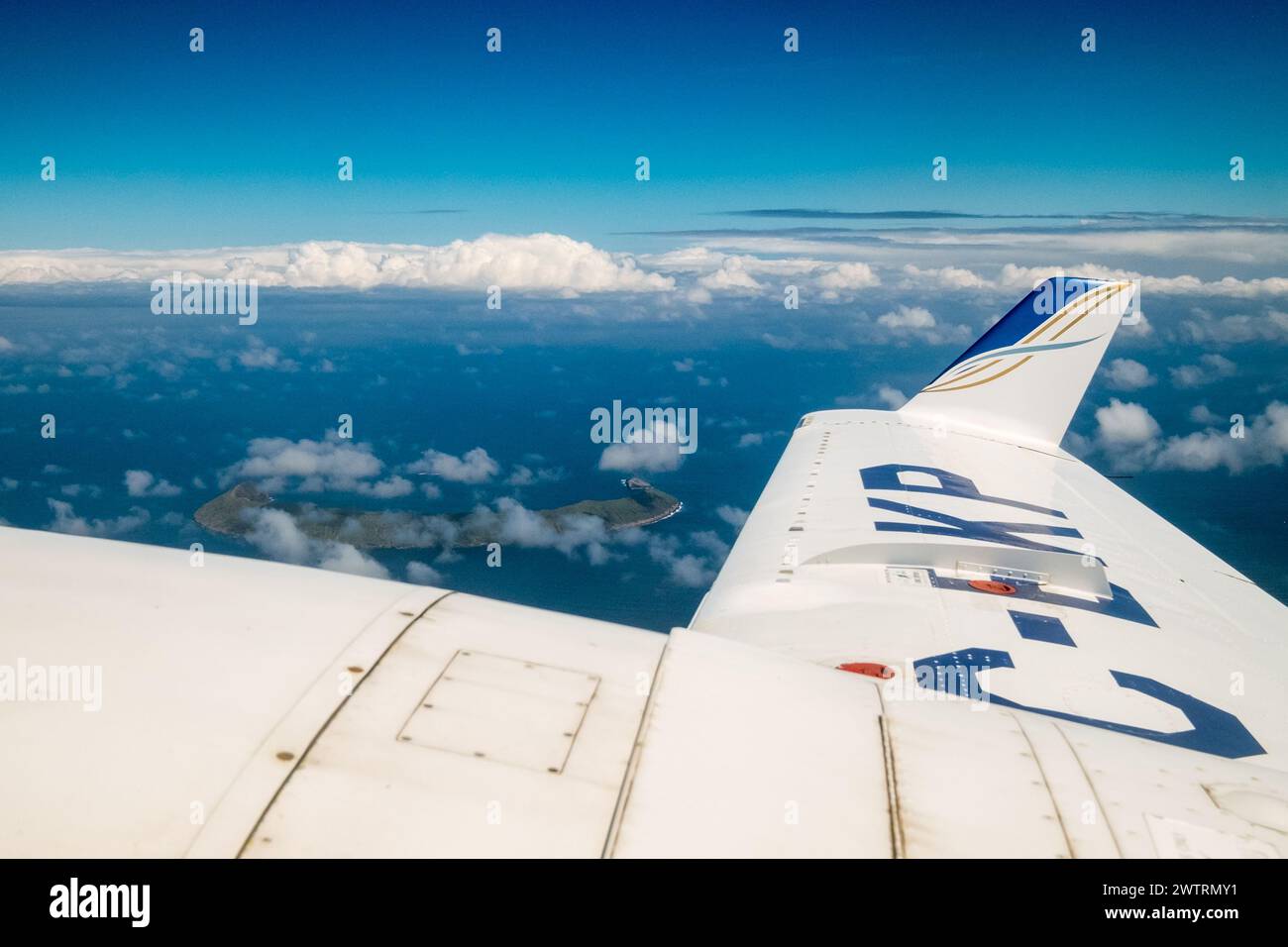 Ein Flugzeug fliegt über dem Ozean mit Wolken am Himmel. Das Flugzeug hat die Buchstaben KP am Schwanz Stockfoto