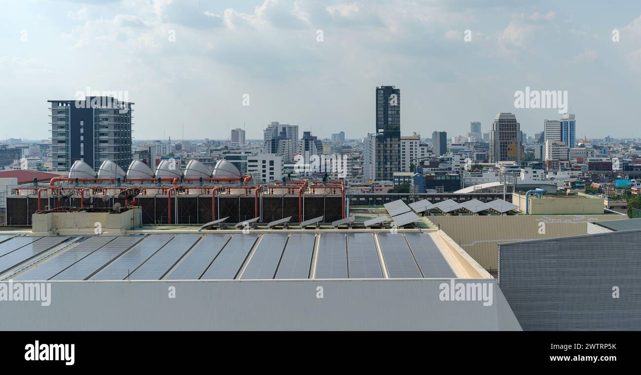 Solarpaneele auf dem Dach, Solarpaneele in geraden, langen Reihen mit Wolkenkratzern im Hintergrund Stockfoto