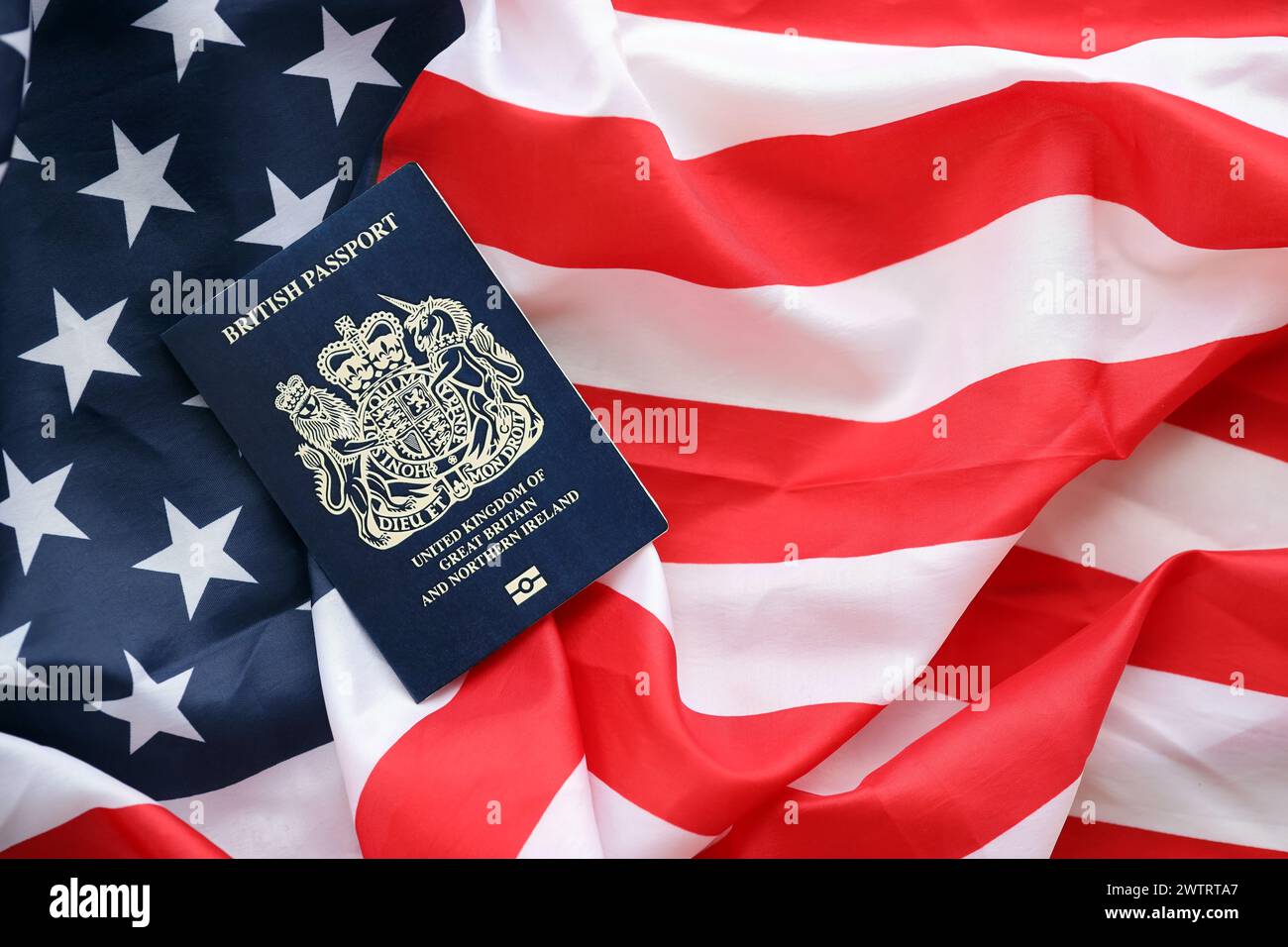 Blauer britischer Pass auf dem Hintergrund der US-Nationalflagge aus nächster Nähe. Tourismus und Diplomatie Stockfoto
