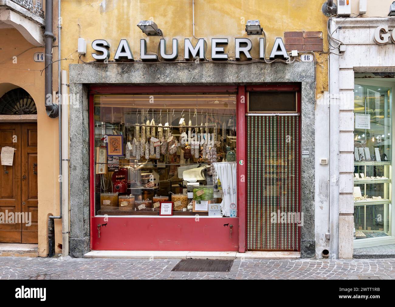 Alte italienische Salumeria (Delikatessengeschäft), Salami hängt im Fenster, Eingang und Schild. Mantua, Lombardei, Italien, Europa, Europäische Union, EU. Stockfoto