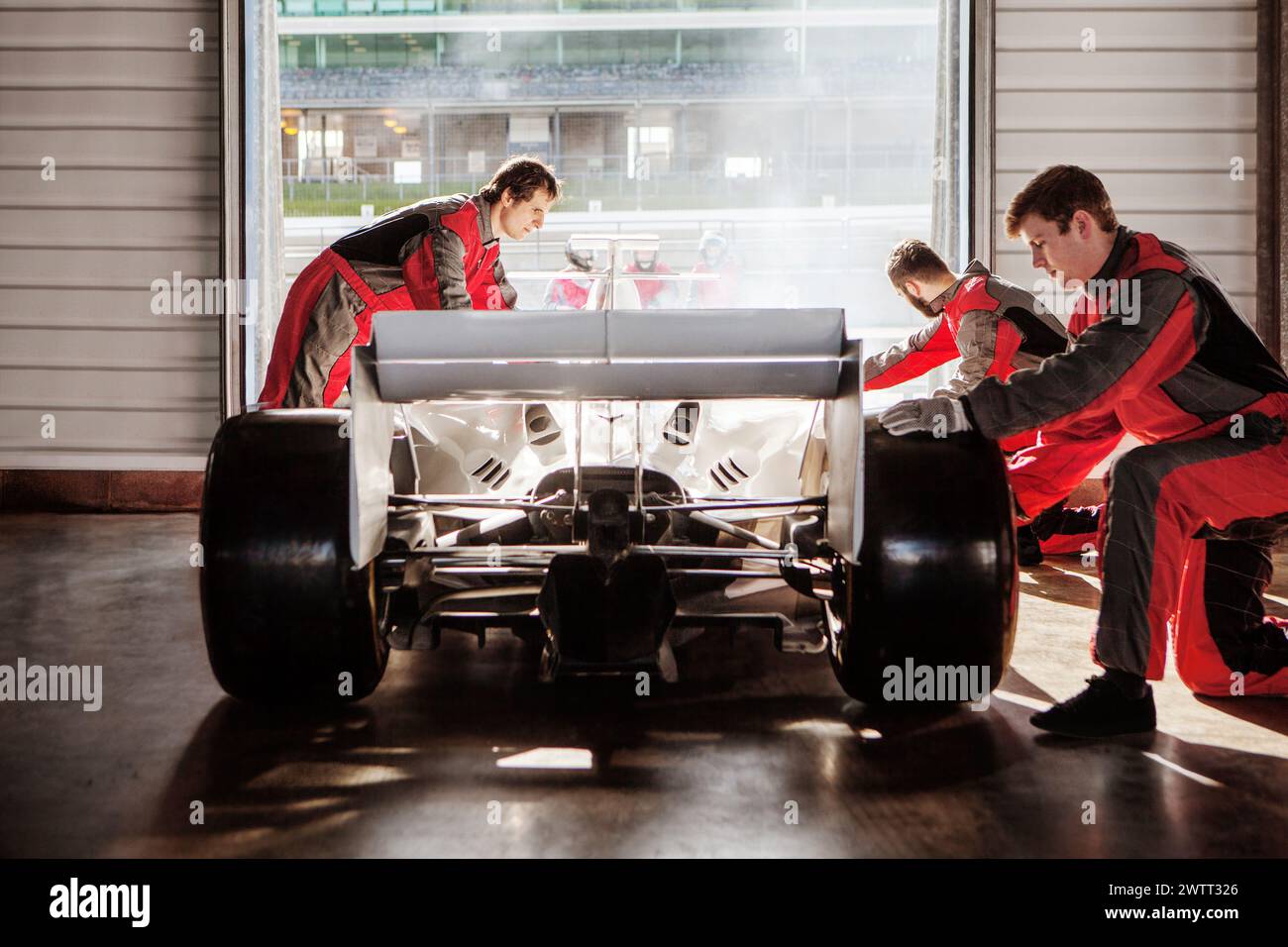 Die Boxencrew arbeitet fleißig an einem Rennwagen in der Garage vor dem Rennen. Stockfoto