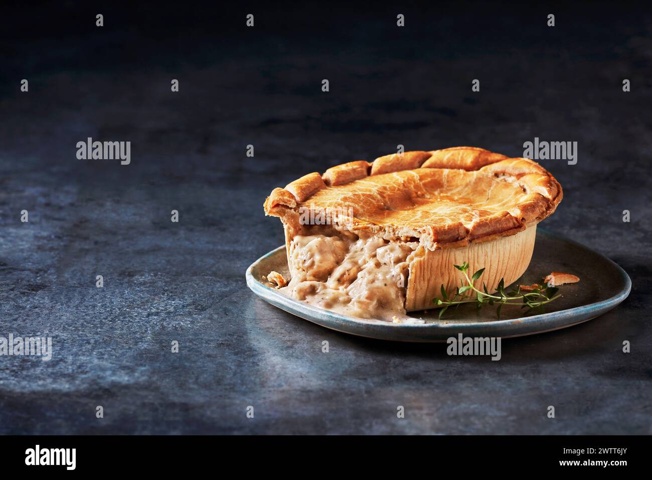 Ein köstlicher Hühnerkopfkuchen auf einem rustikalen Teller, garniert mit frischen Kräutern. Stockfoto