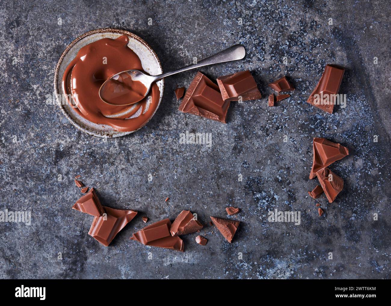 Geschmolzene Schokoladenfreude umgeben von gebrochenen Schokoladenstückchen. Stockfoto
