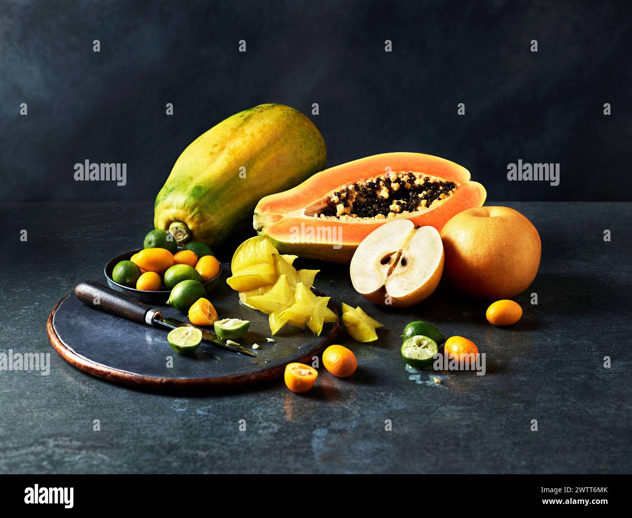 Eine lebendige Ausstellung exotischer Früchte, kunstvoll auf einer dunklen strukturierten Oberfläche angeordnet. Stockfoto