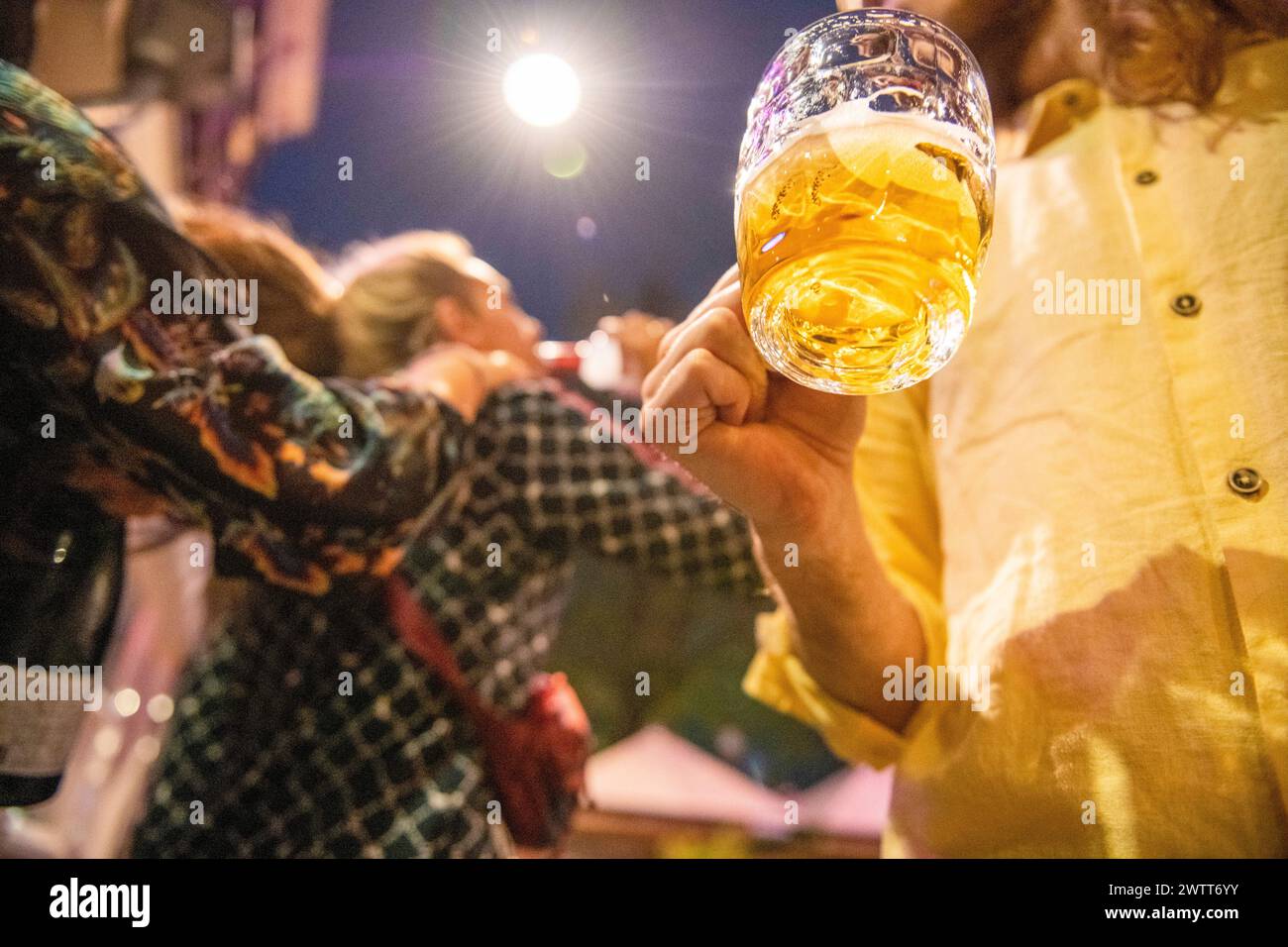 Feiern Sie die Nacht mit einem erhöhten Glas Bier in einer lebhaften Straßenlage. Stockfoto