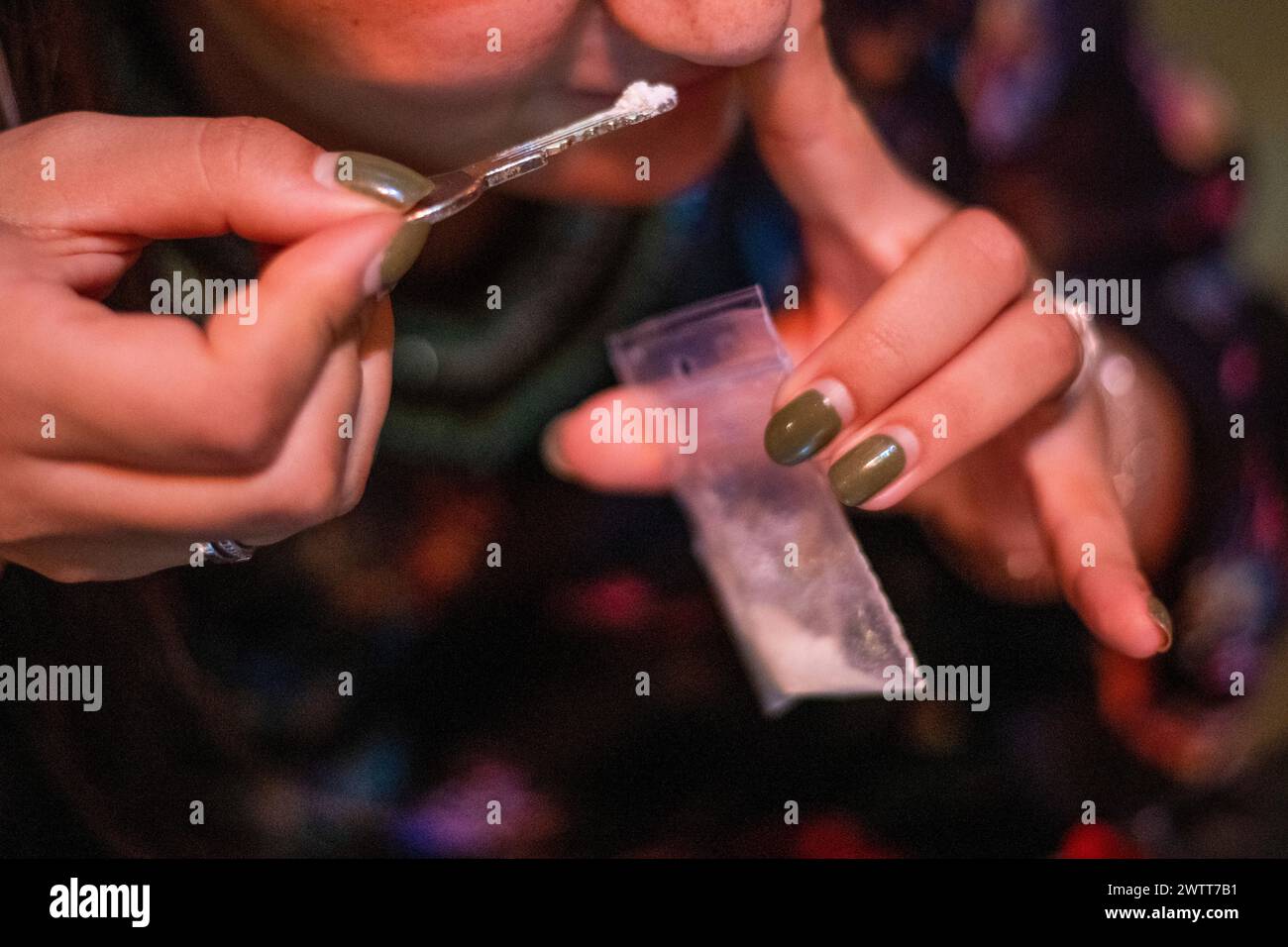 Eine drogensüchtige Frau schnüffelt Kokain aus einem Löffel in einem Nachtclub Stockfoto