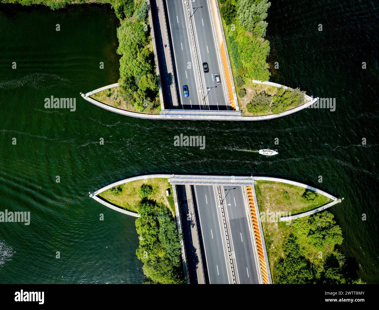 Aus der Vogelperspektive auf eine Brücke über einen ruhigen Fluss mit vorbeifahrenden Autos und einem Boot Stockfoto
