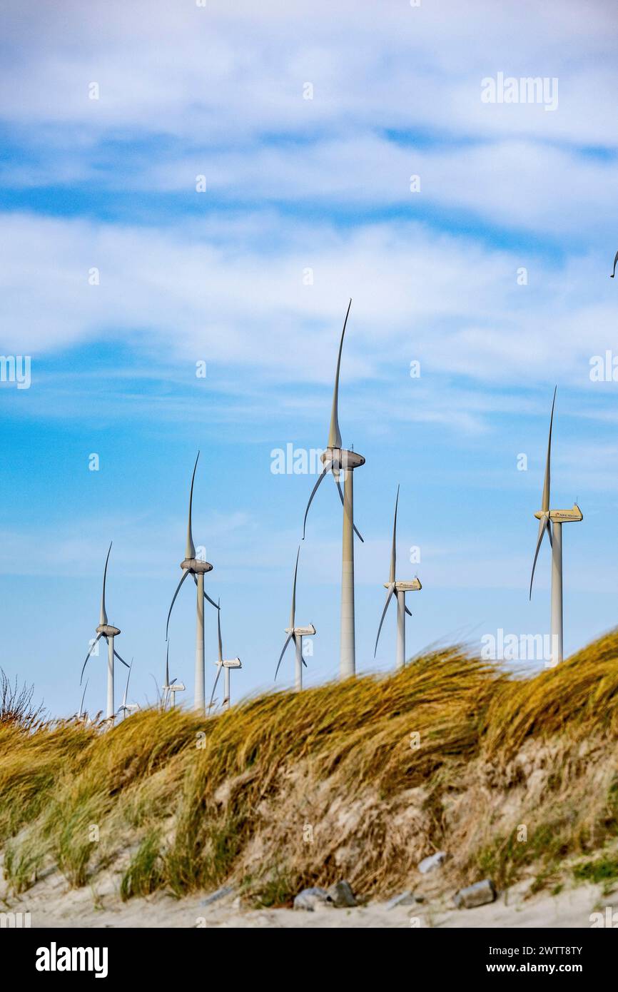 Eine lebhafte Landschaft mit Windturbinen, die über Sanddünen ragen. Stockfoto