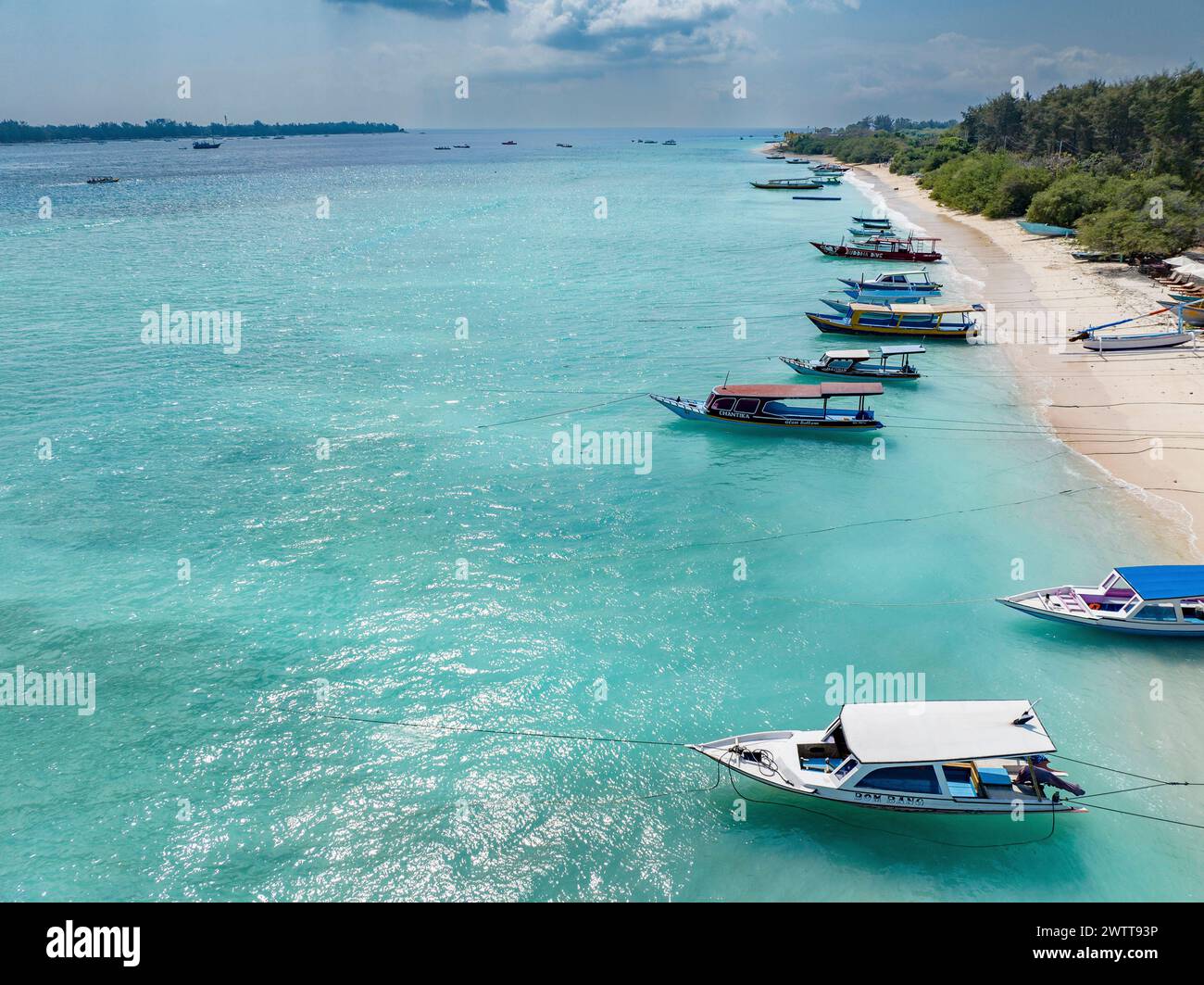 Ein ruhiger tropischer Strand mit Booten, die in klarem, blauem Wasser vertäut sind Stockfoto