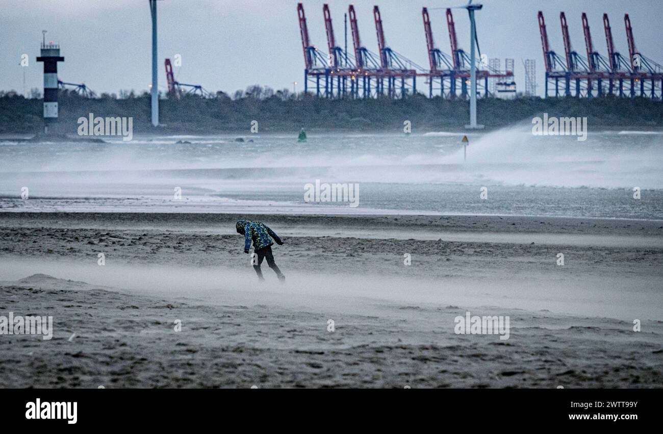 Eine einsame Figur macht einen windigen Tag an einem einsamen Strand. Stockfoto