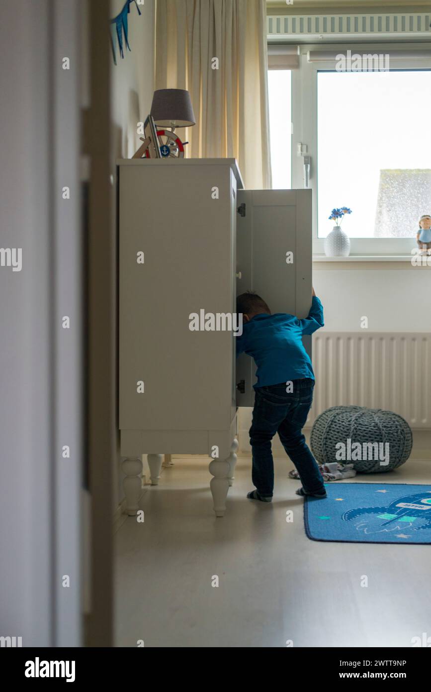 Neugieriges Kind, das zu Hause in einen Schrank guckt Stockfoto