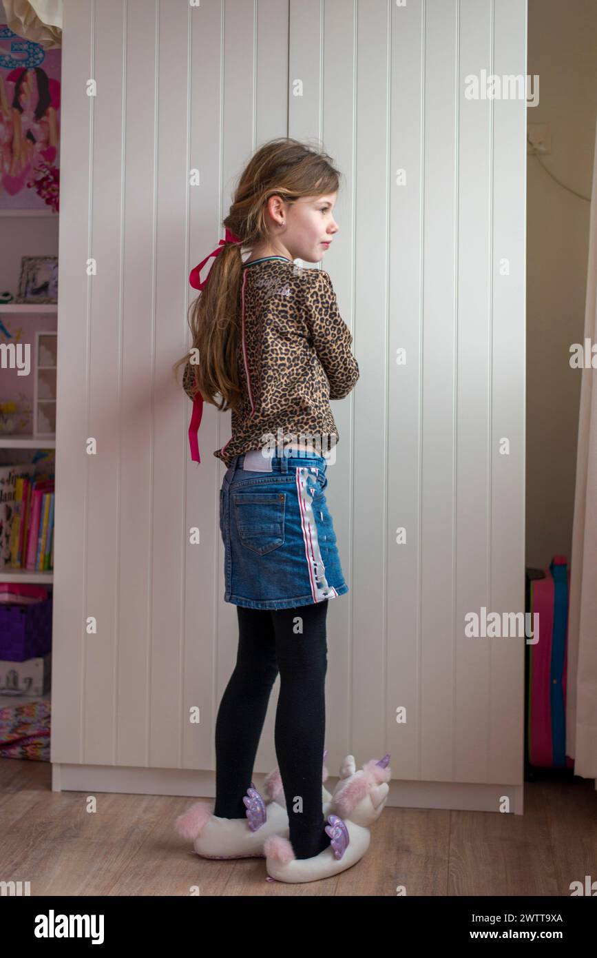 Ein junges Mädchen in verspielter Haltung mit einem Oberteil mit Leopardenmuster und einem Jeansrock Stockfoto