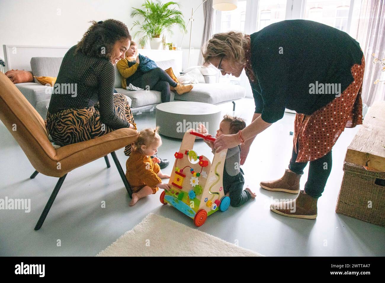 Spaß für die ganze Familie, während ein Kleinkind seine ersten Schritte mit Ermutigung macht. Stockfoto