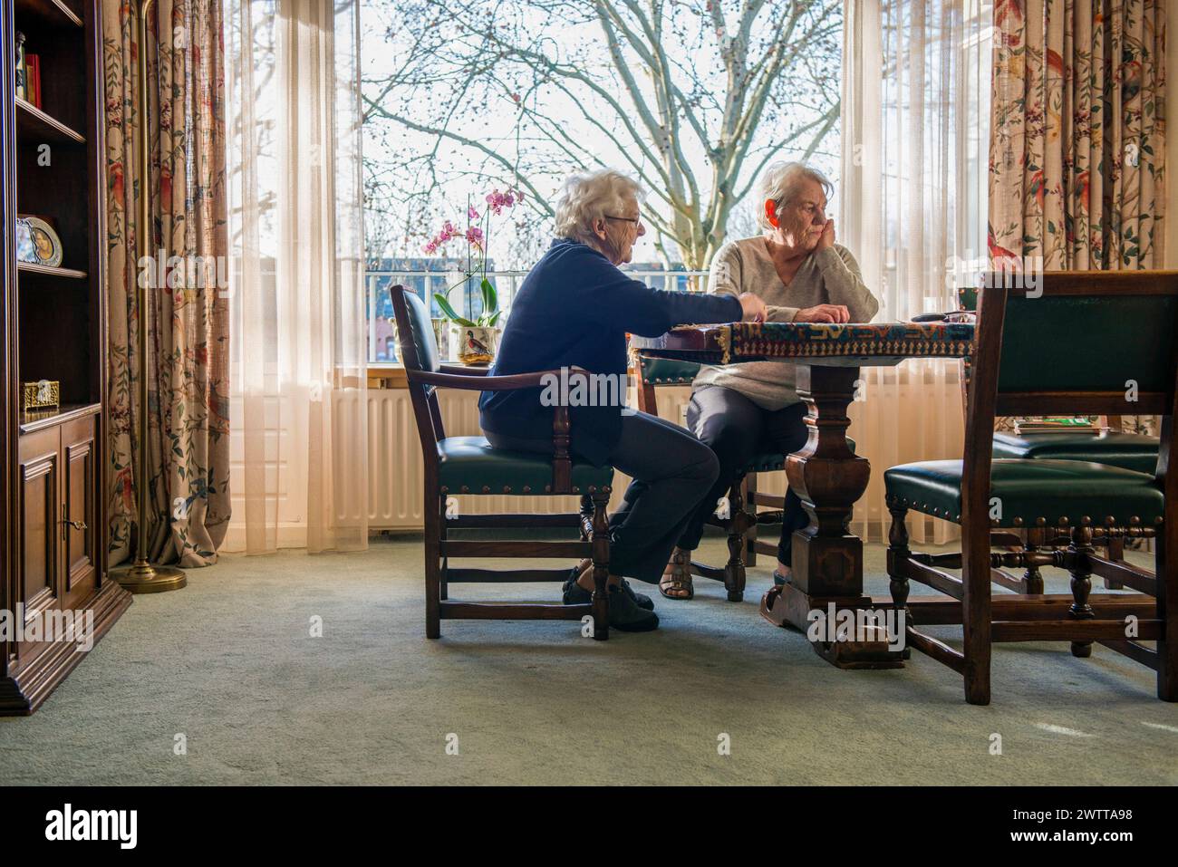 Ein älteres Ehepaar hat sich an einem durchdachten Schachspiel am Fenster beteiligt. Stockfoto