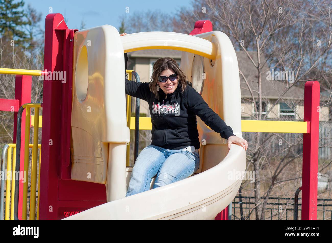 Lächelnde Frau auf einer Spielplatzrutsche Stockfoto