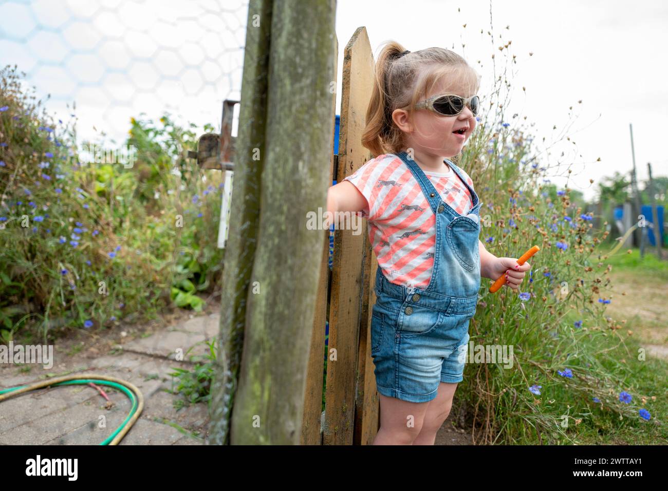 Kleines Mädchen, das einen sonnigen Tag im Garten mit ihrem Seifenstab genießt. Stockfoto