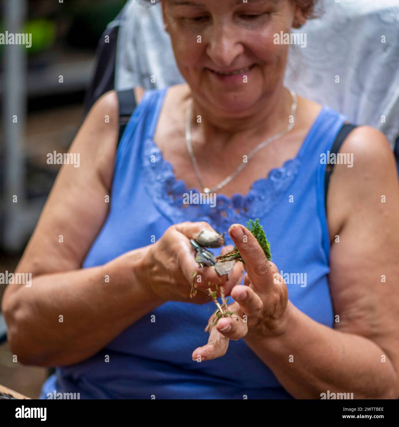 Eine Frau lächelt, während sie zärtlich einen kleinen Vogel in den Händen hält. Stockfoto
