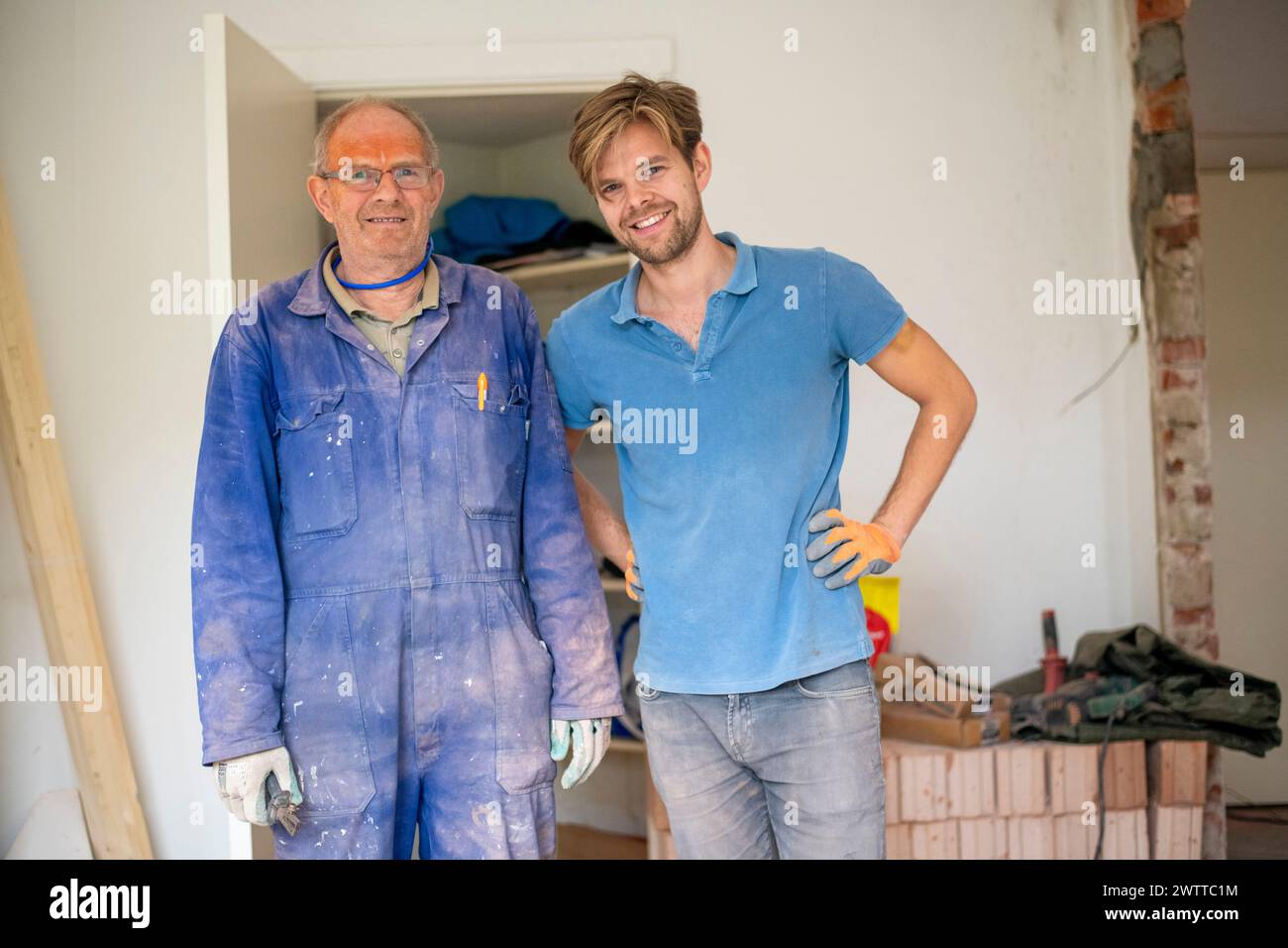 Ein lächelnder Bauarbeiter und Hausbesitzer posierte während eines Renovierungsprojekts Stockfoto