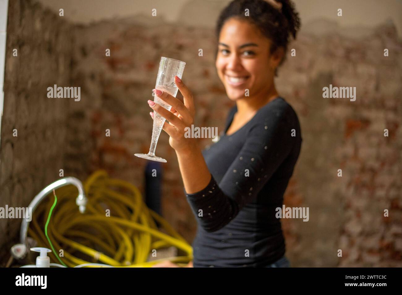 Eine junge Frau genießt einen feierlichen Toast bei einer zwanglosen Versammlung Stockfoto