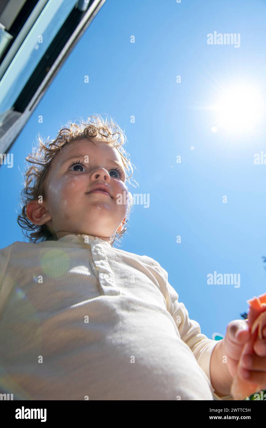 Ein Kleinkind, das an einem sonnigen Tag in den Himmel blickt Stockfoto