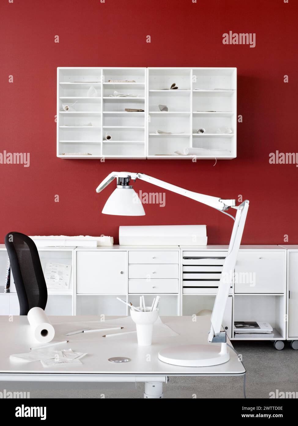 Ein minimalistisches weißes Home Office mit einer leuchtend roten Wand Stockfoto