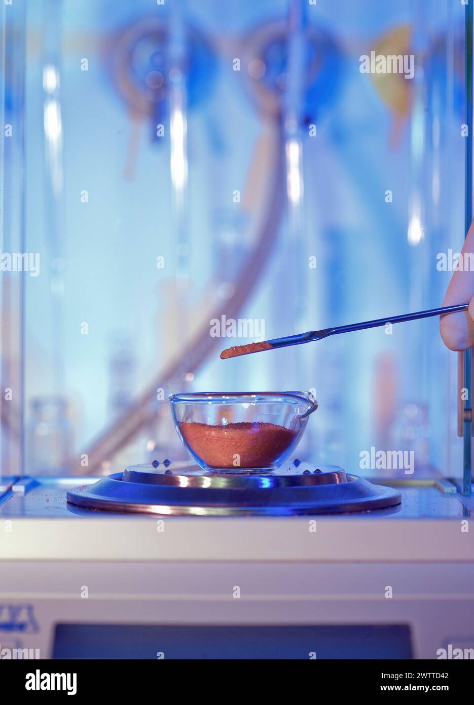 Die Hand eines Wissenschaftlers wiegt eine pulverförmige Substanz in einem Labor Stockfoto
