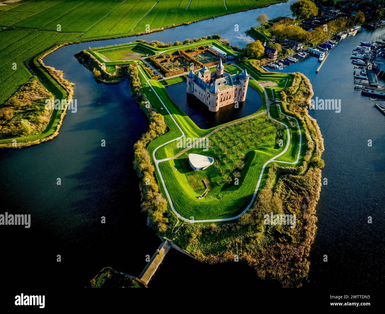Blick aus der Vogelperspektive auf ein historisches Schloss, umgeben von Wasserstraßen in der Abenddämmerung Stockfoto