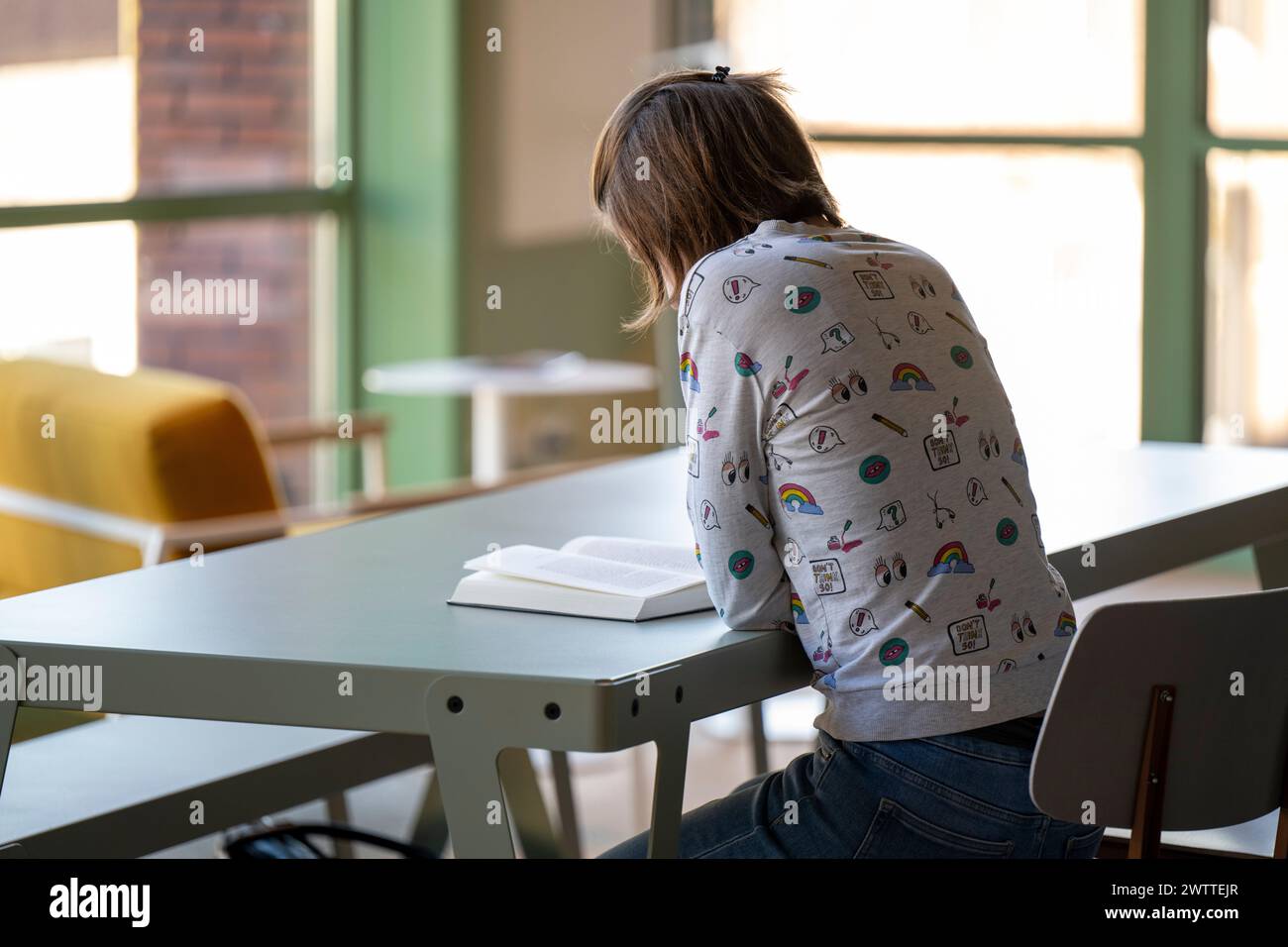 Junger Erwachsener, der intensiv an einem Bibliothekstisch studiert. Stockfoto