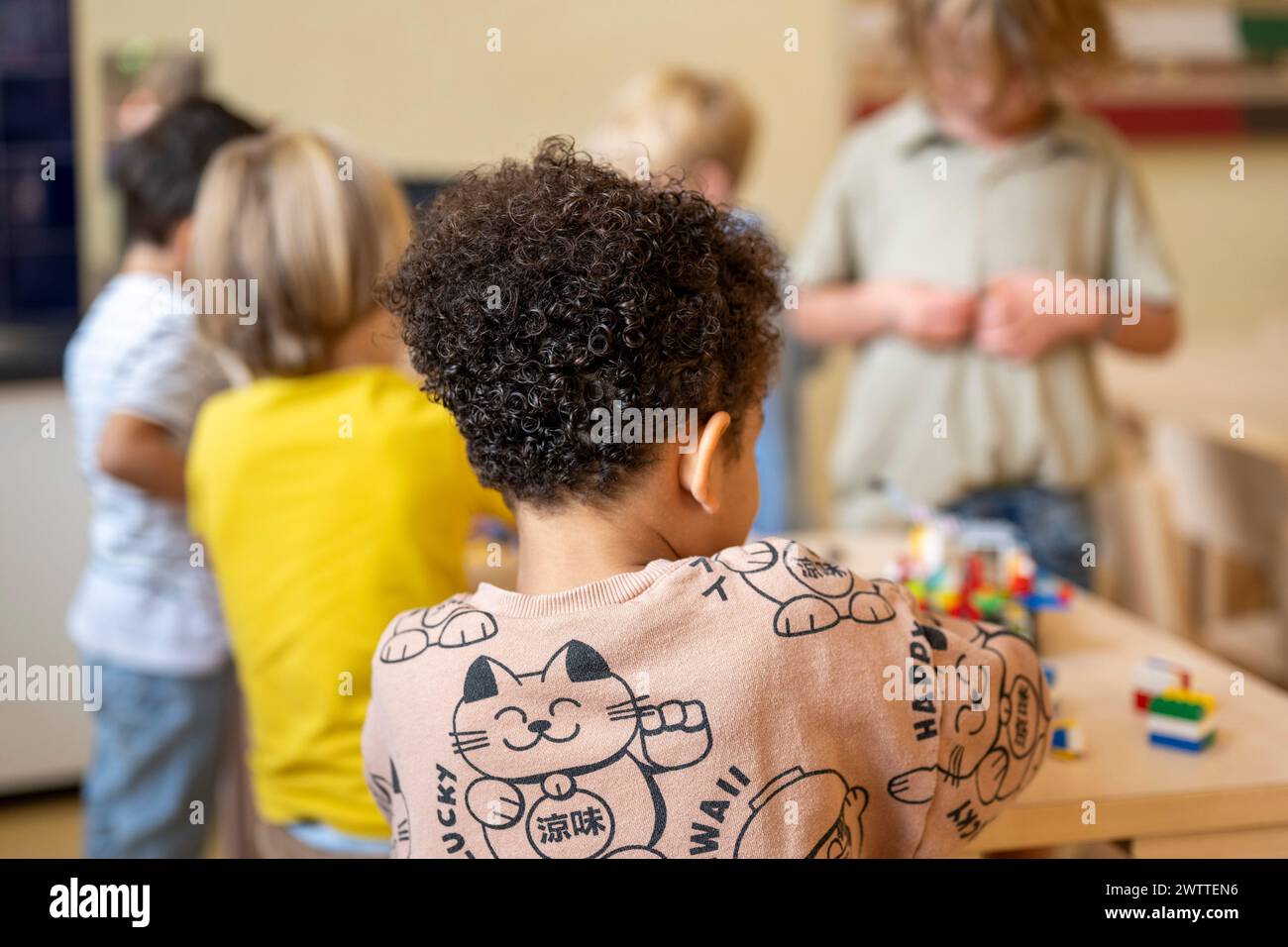 Neugieriges Kind, das Gleichaltrige während des Spielens beobachtet. Stockfoto