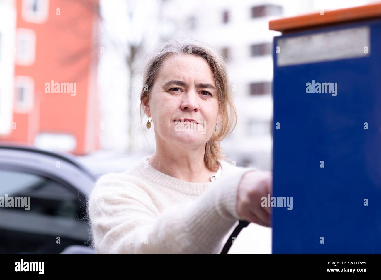 Frau, die ihr Elektroauto auflädt Stockfoto