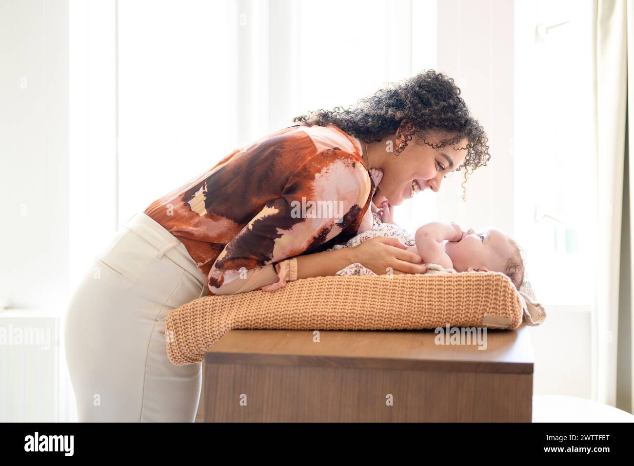 Ein zärtlicher Moment zwischen einer Mutter und ihrem Baby, das in sanftes, natürliches Licht getaucht ist. Stockfoto
