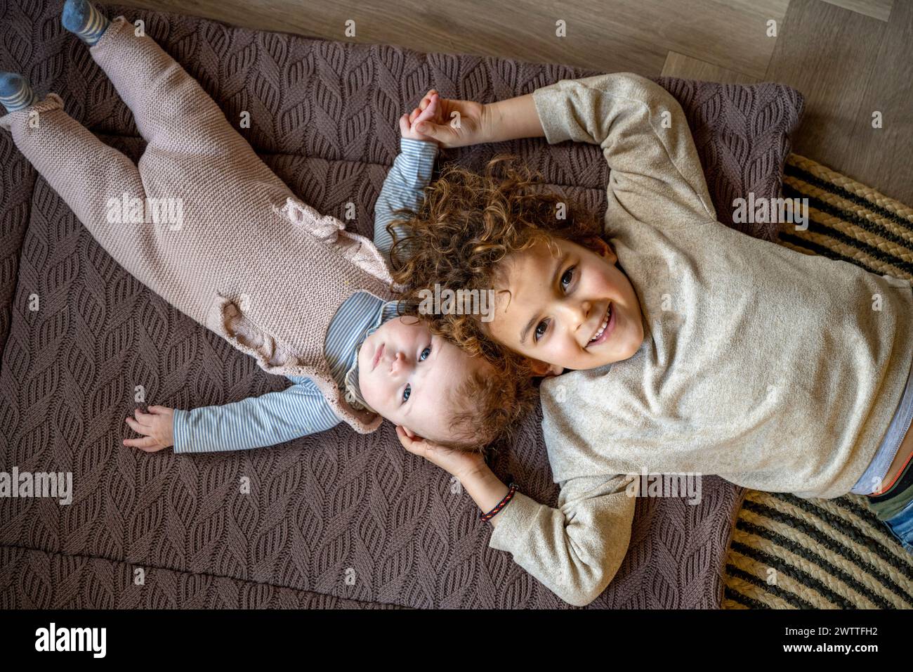 Zwei fröhliche Geschwister, die auf dem Boden spielen Stockfoto