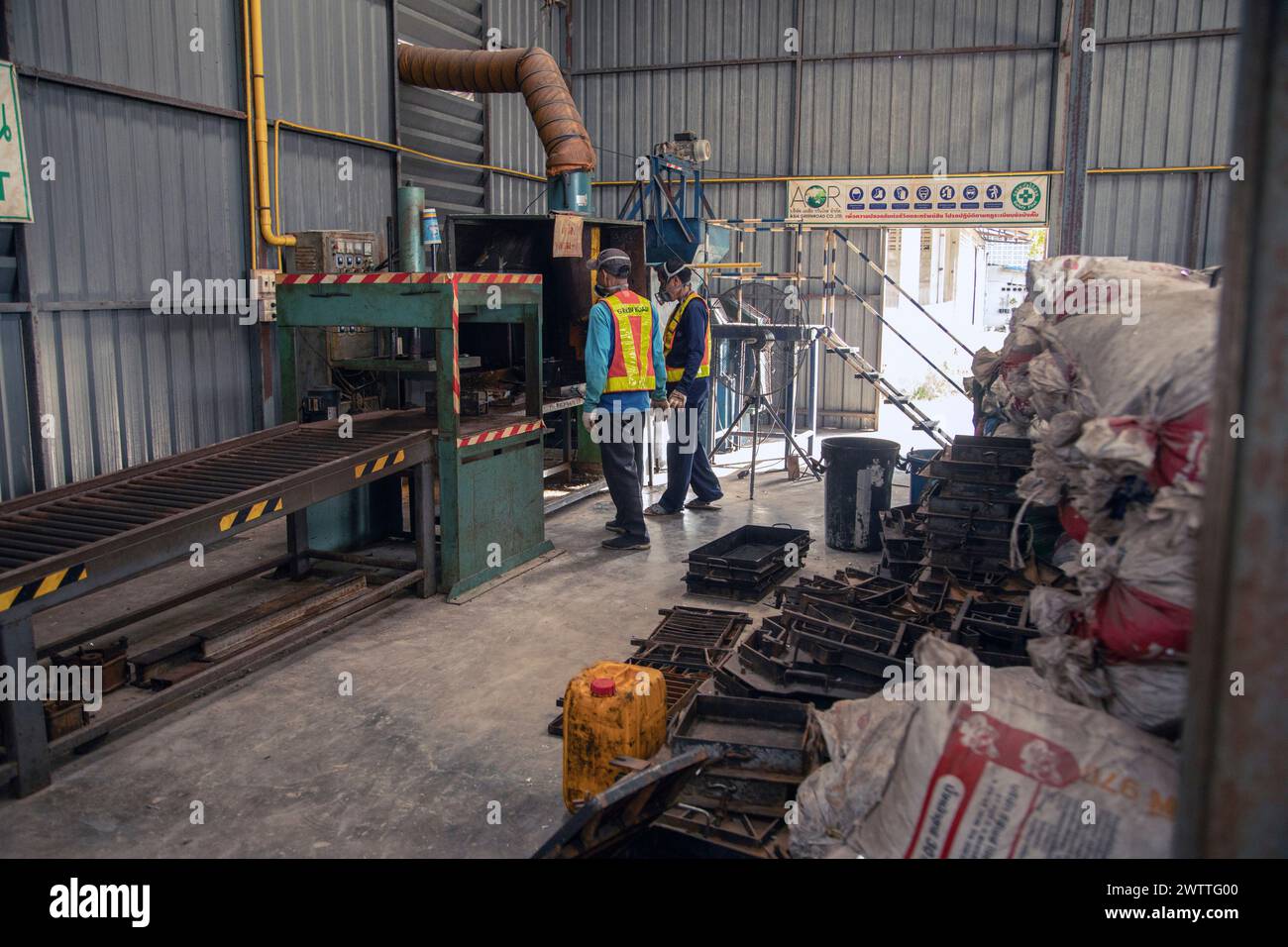 Arbeiter, die Maschinen in einer Kunststoffrecyclingfabrik in Thailand überwachen Stockfoto