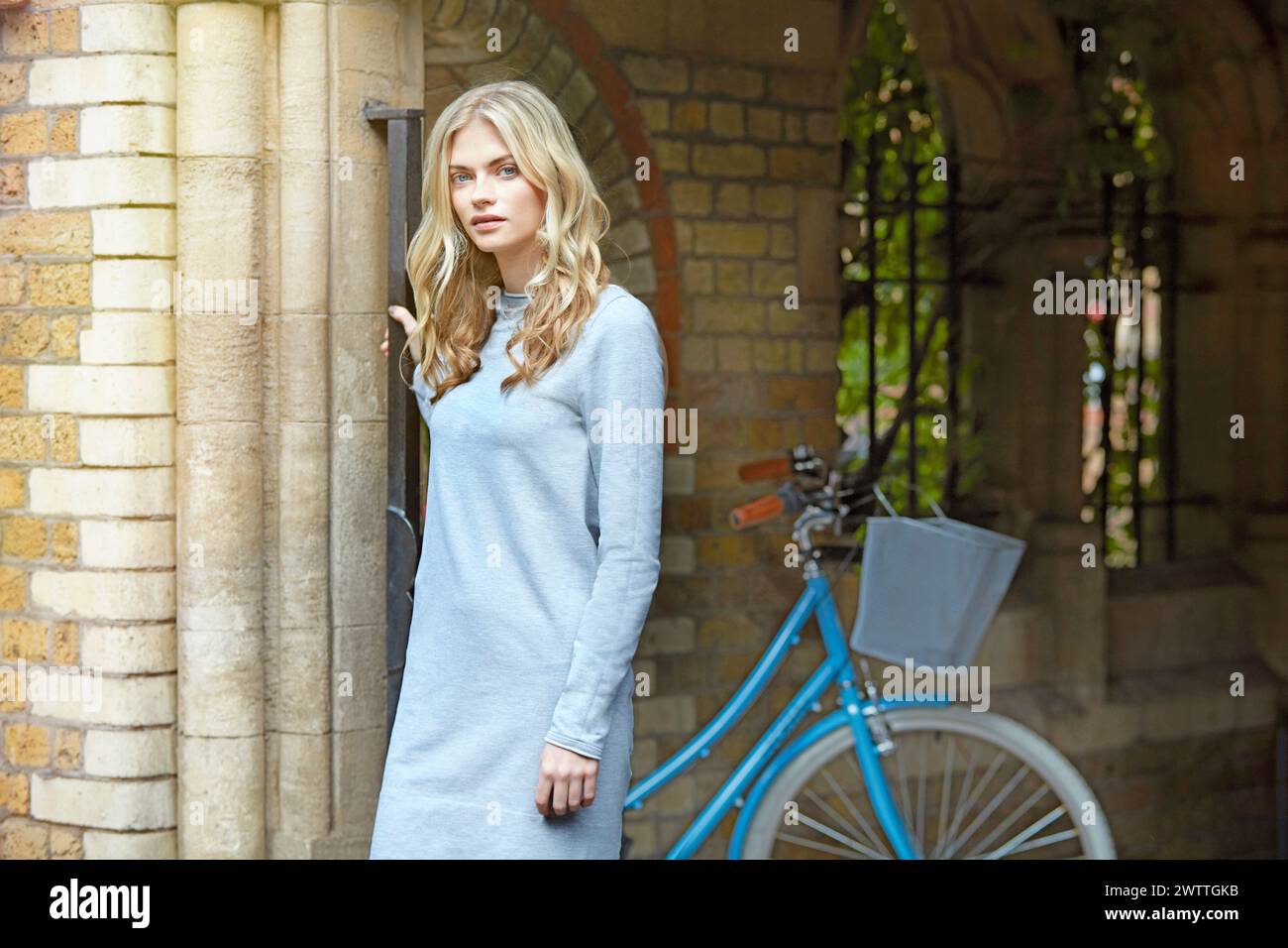 Frau an einem Gebäude mit blauem Fahrrad Stockfoto
