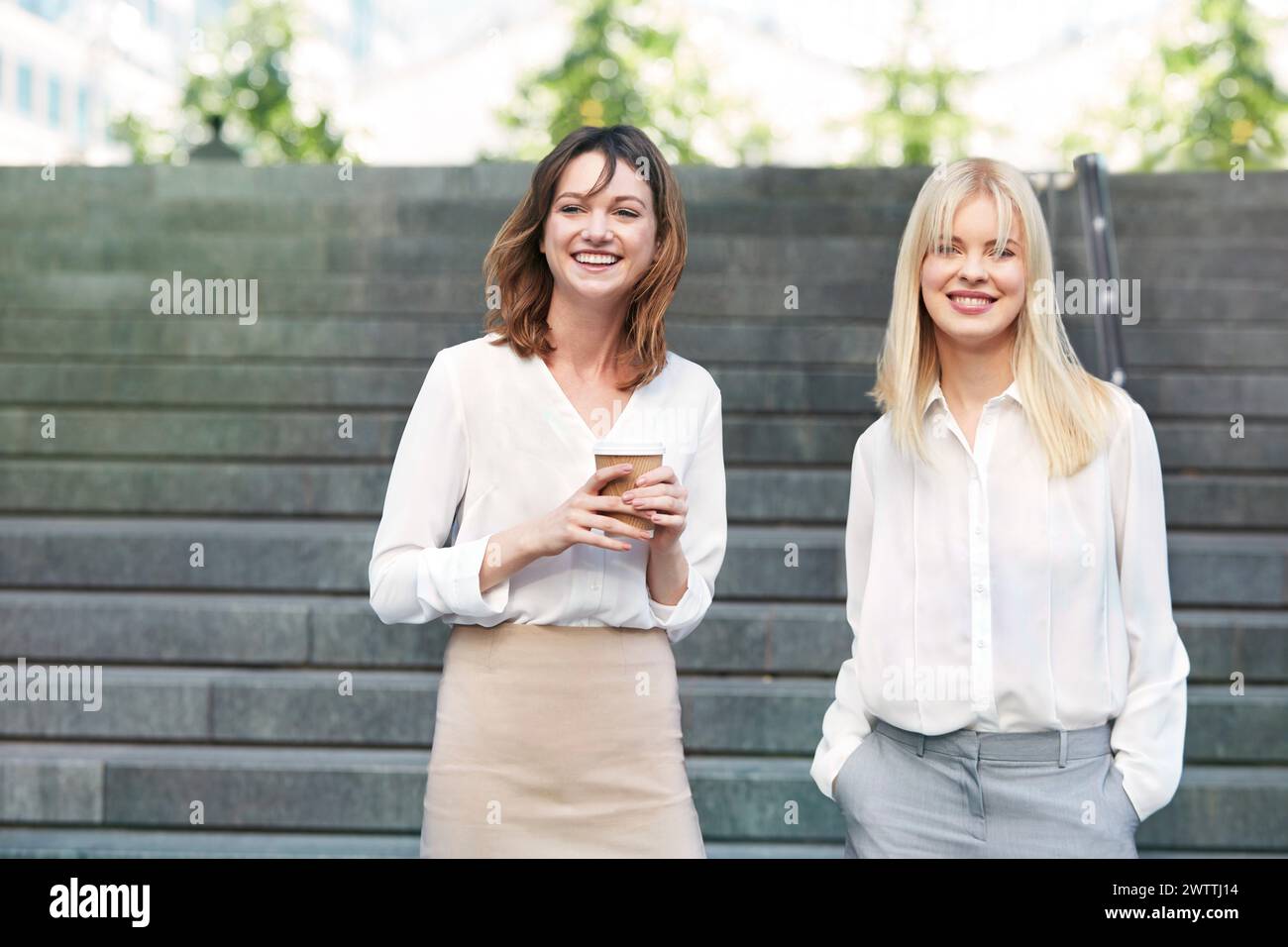 Zwei Frauen lächeln auf den Stufen im Freien Stockfoto