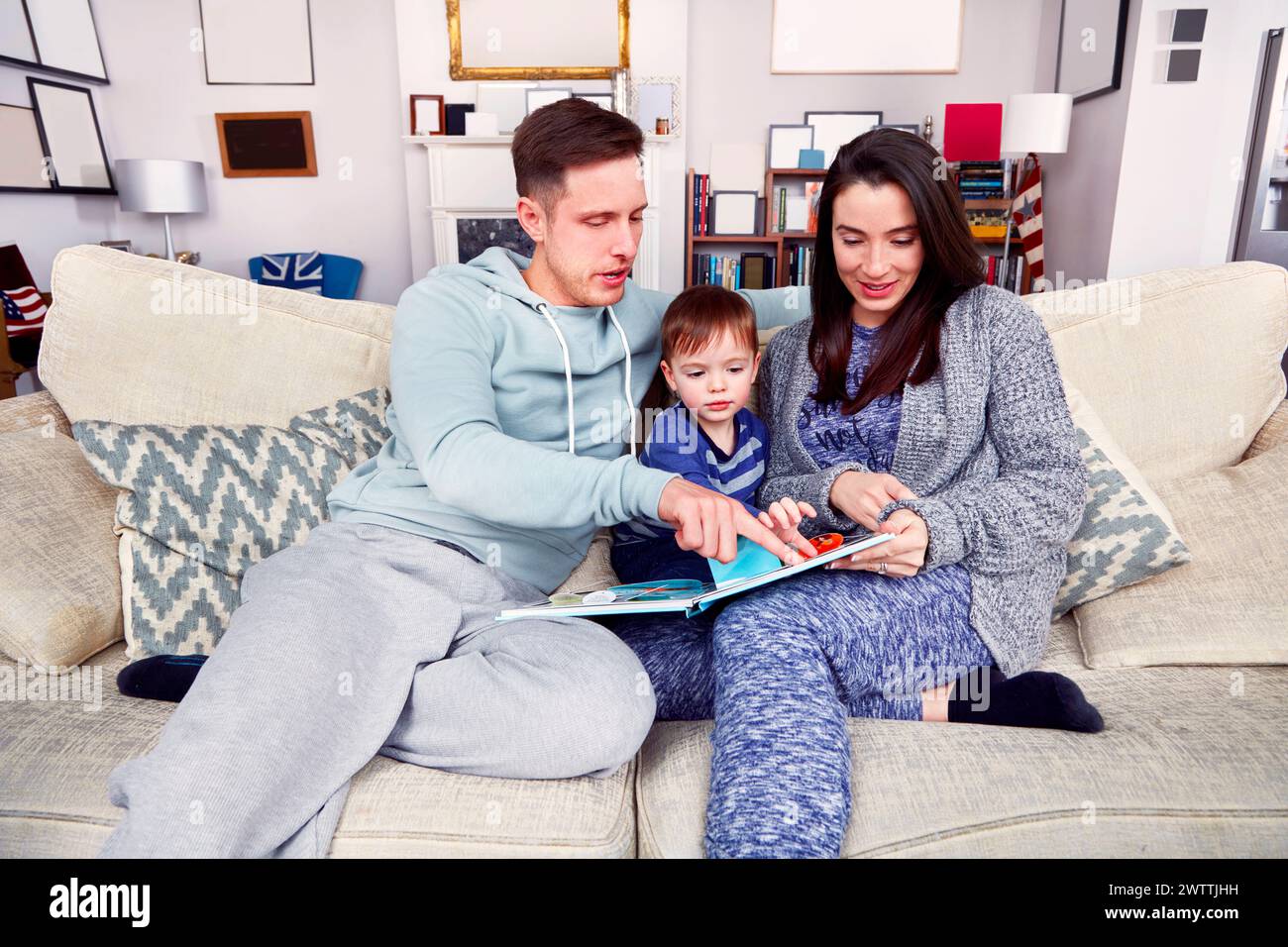 Familie liest ein Buch zusammen auf der Couch Stockfoto