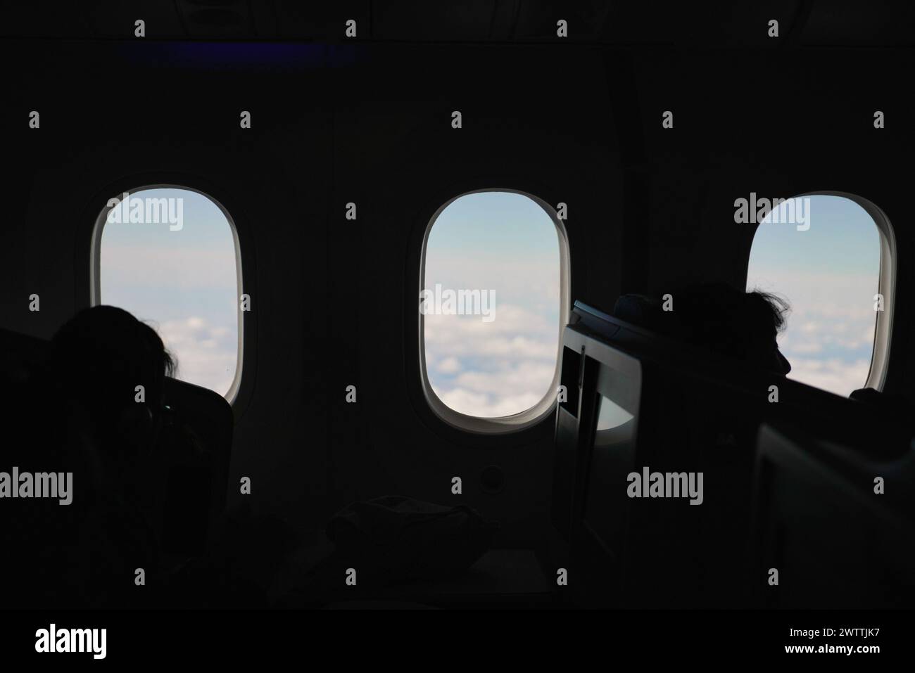 Flugzeugfenster mit Blick auf Himmel, Wolken und Flügel. Flugzeugkabine im Flug Stockfoto
